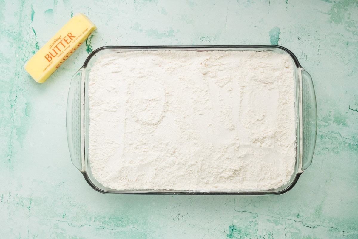 Yellow cake mix poured on top of the strawberry filling in a baking dish.