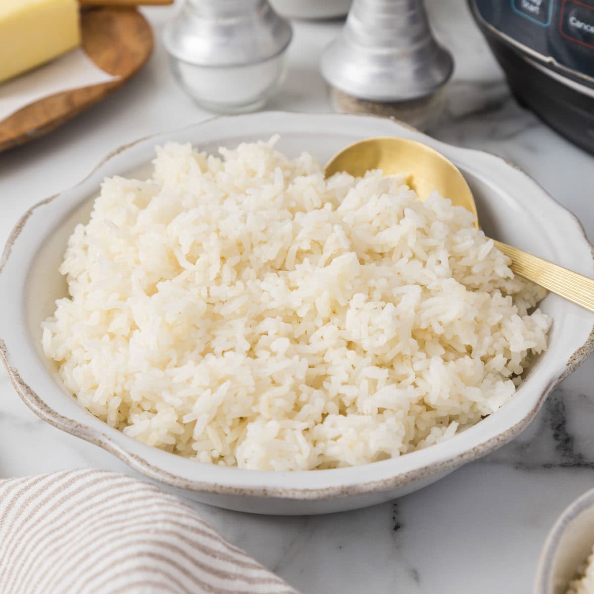 A bowl of white rice with an instant pot in the background.