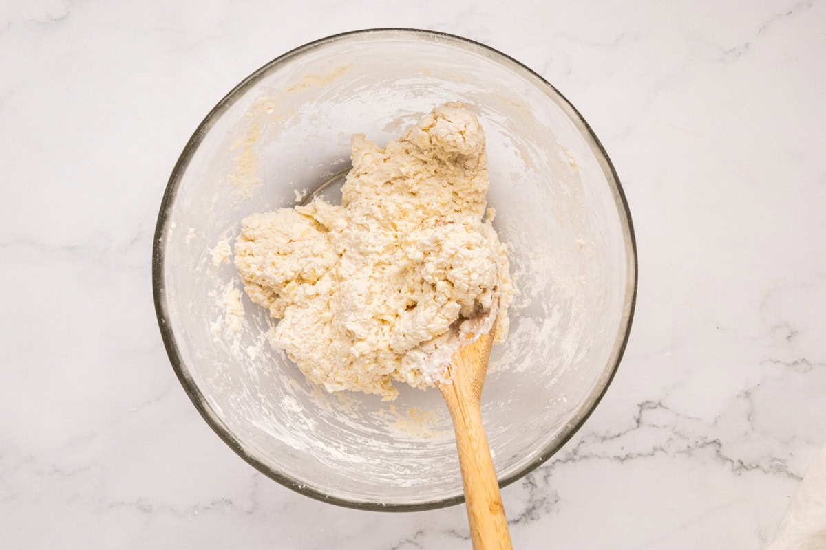 Buttermilk stirred together to form a dough in a bowl.
