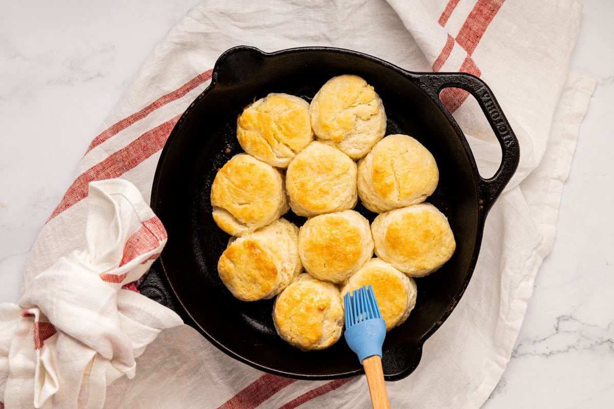 Brushing the top of freshly baked buttermilk biscuits with melted butter.