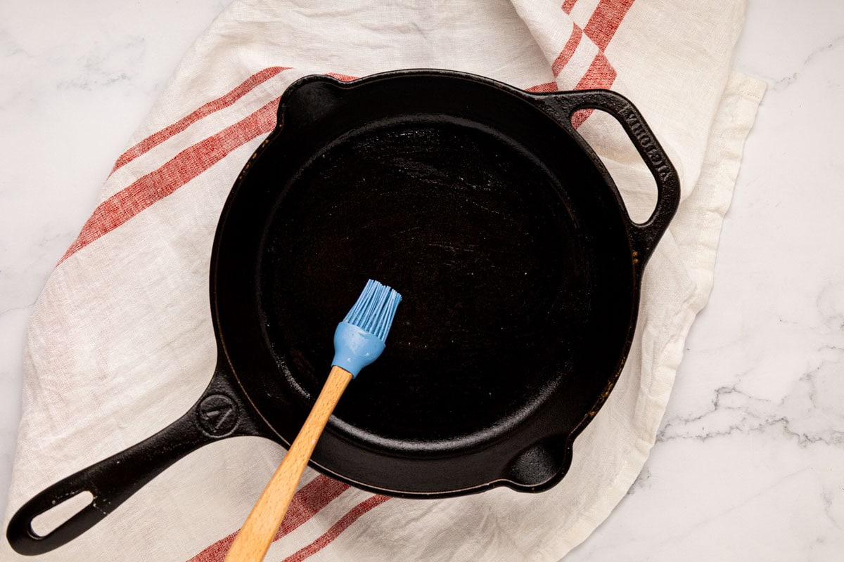 Brushing a cast iron skillet with butter.