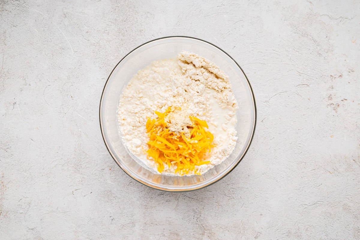 Cheddar bay biscuit mix, milk and shredded cheese in a bowl.