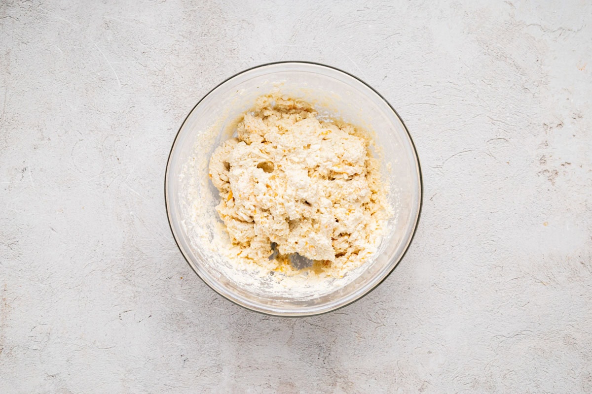 Cheddar bay biscuit mix in a bowl mixed with milk and shredded cheese.