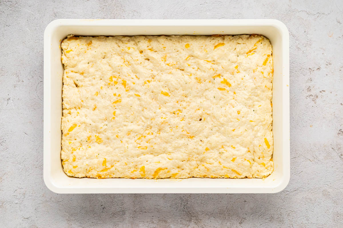 Baked cheddar bay biscuit mixture in the bottom of a baking dish.