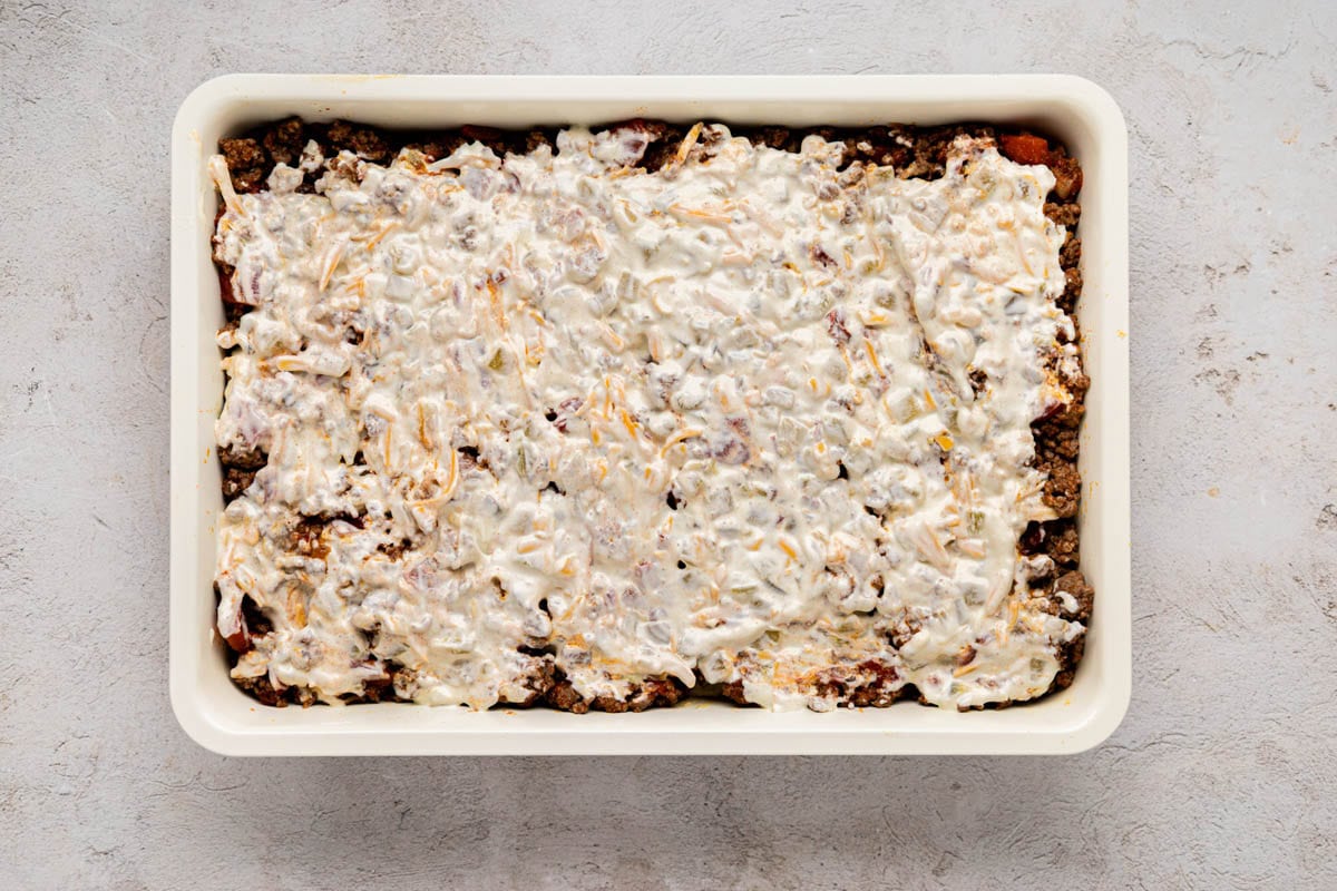Creamy mayo layer placed on top of ground beef layer.