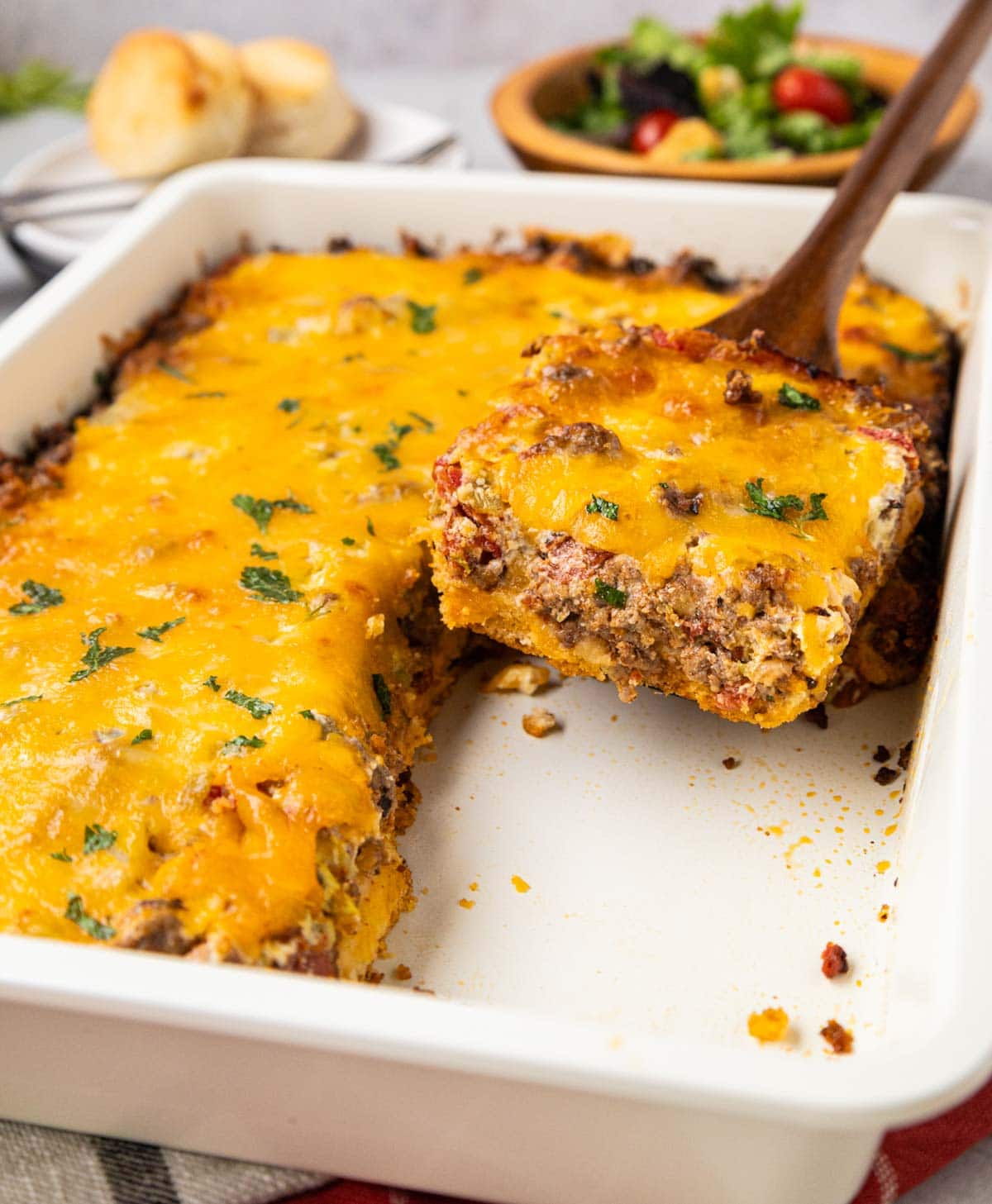 Wooden spatula scooping up a portion of cattle drive casserole form the baking dish.