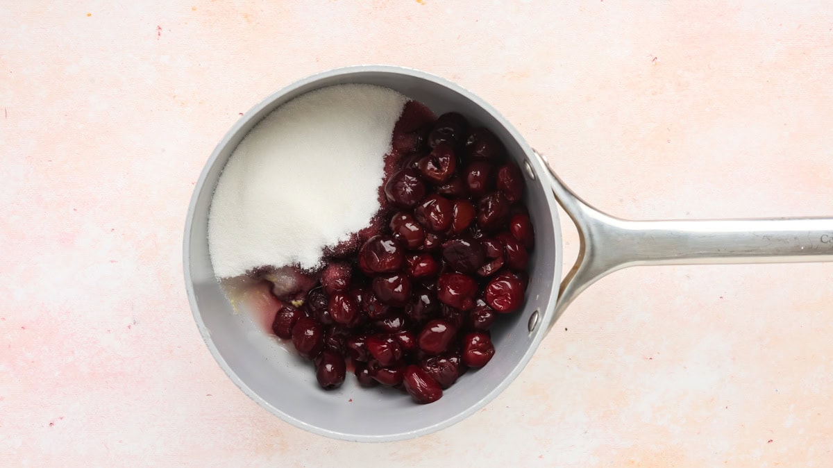 Fresh cherries, sugar, and lemon juice in a saucepan.