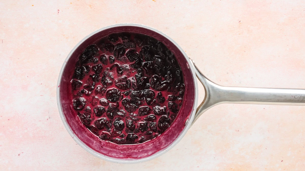 Cherries simmering with sugar and lemon juice in a saucepan.