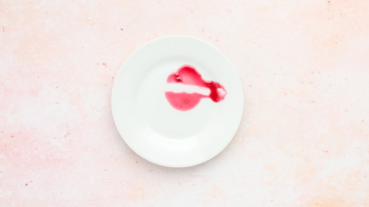 Cherry jam on a plate with a streak through it to show the thick texture.