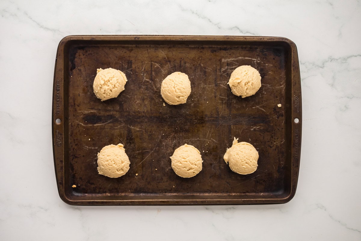 Sugar cookie dough balls on a sheet pan.