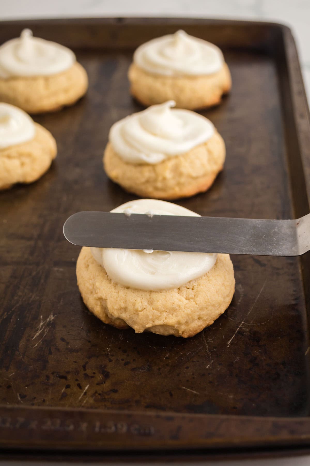 Using a spatula to frost the top of the cookies.