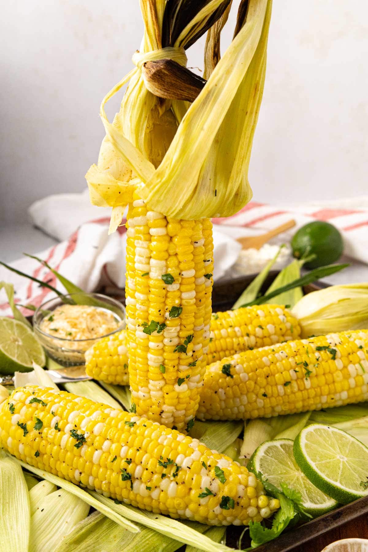 Holding up one grilled corn vertically so you can see all the plump kernels on the cob.
