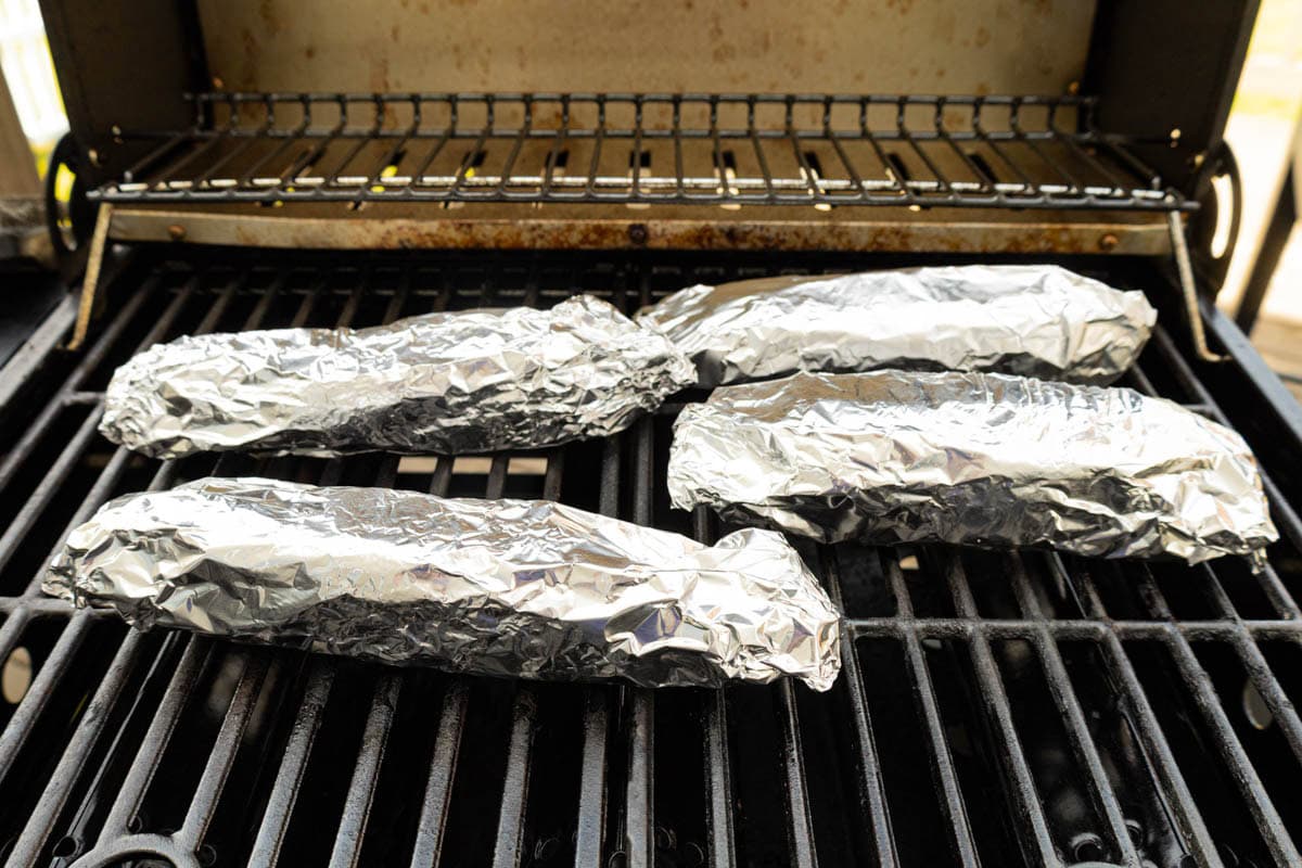Foil wrapped corn on the grill.