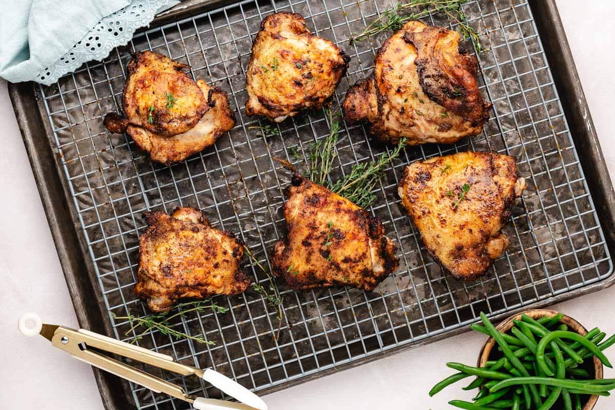 Finished baked chicken thighs on a sheet pan with a wire rack.