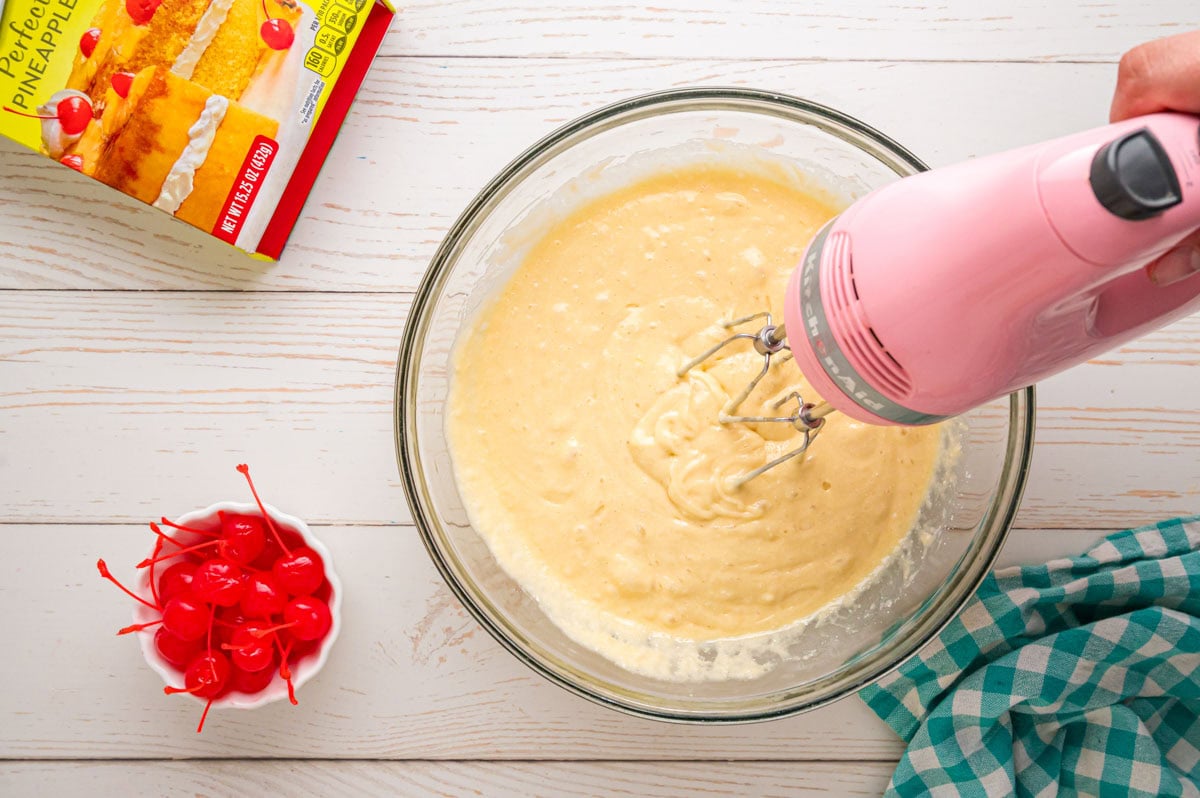 A hand mixer blending the cake batter together.