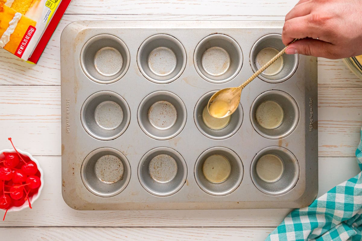 Spooning melted butter into into the cupcake wells.