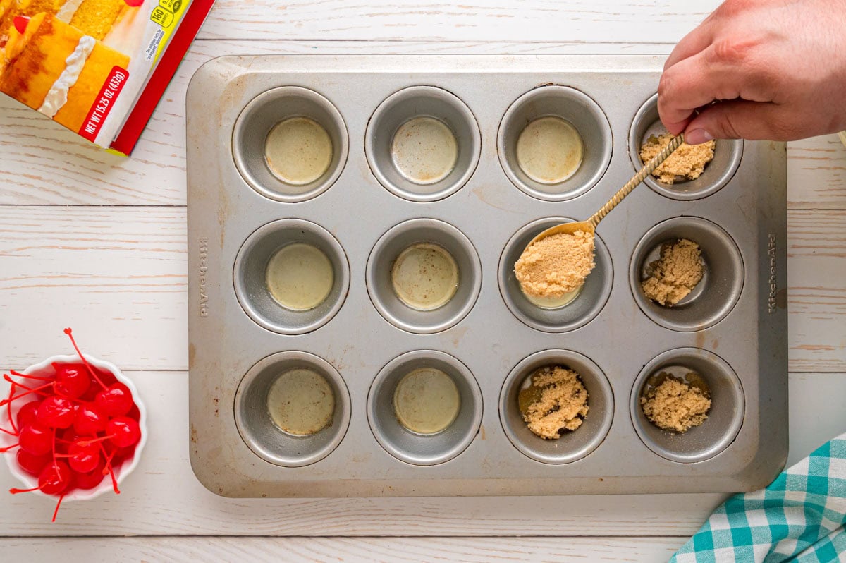 Spooning brown sugar into into the cupcake wells.