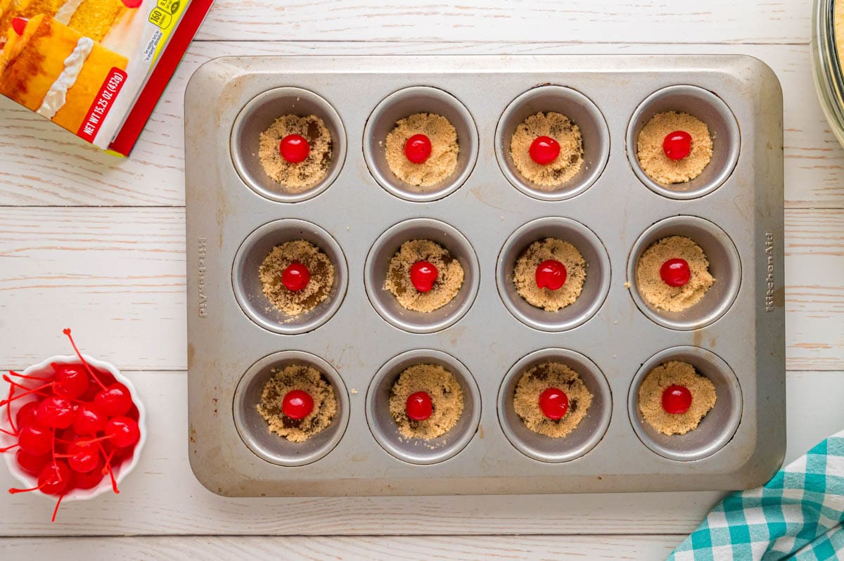 Cherries added to the center of the cupcake wells.