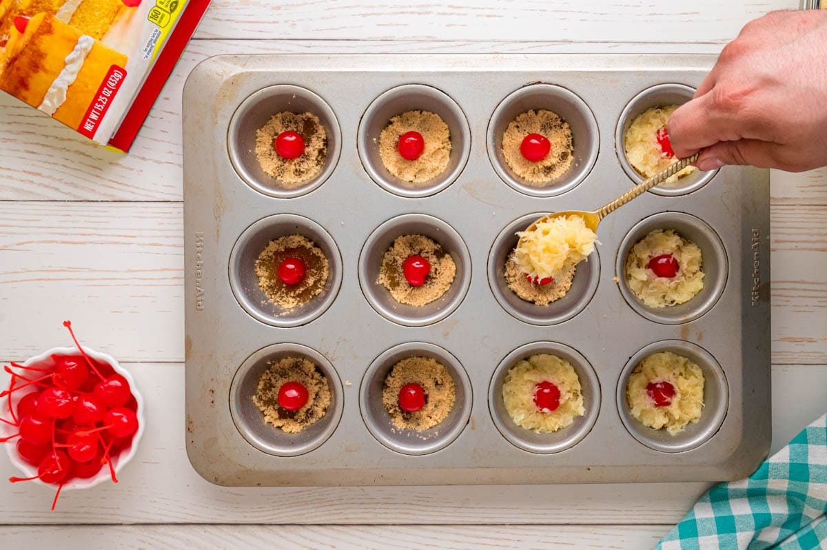 Spooning brown sugar around each cherry in the cupcake wells.