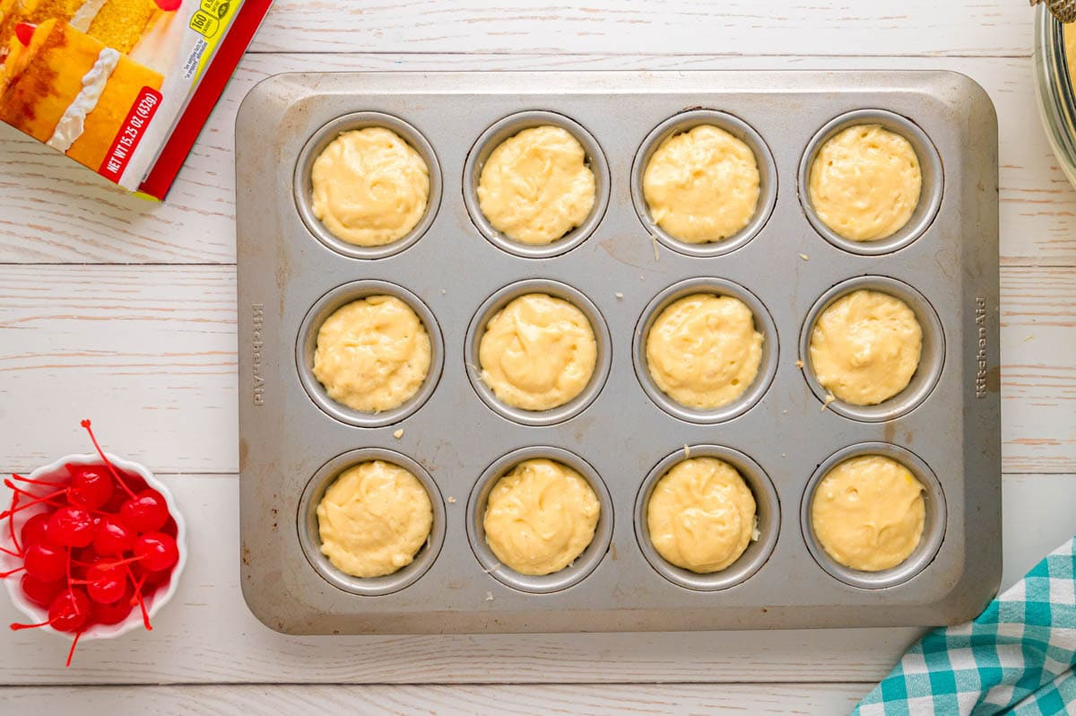 Pineapple cake batter filling all the wells in the muffin tins.