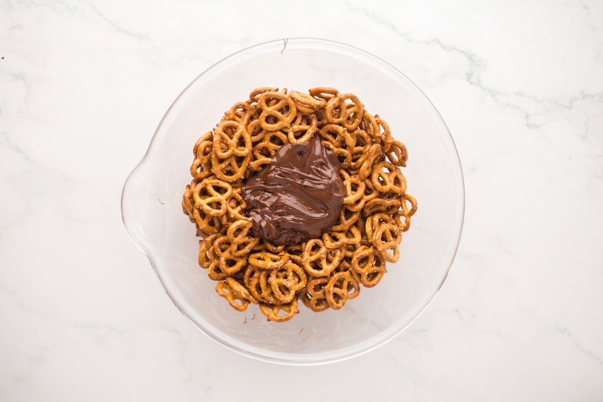Melted chocolate poured over pretzels in a bowl.