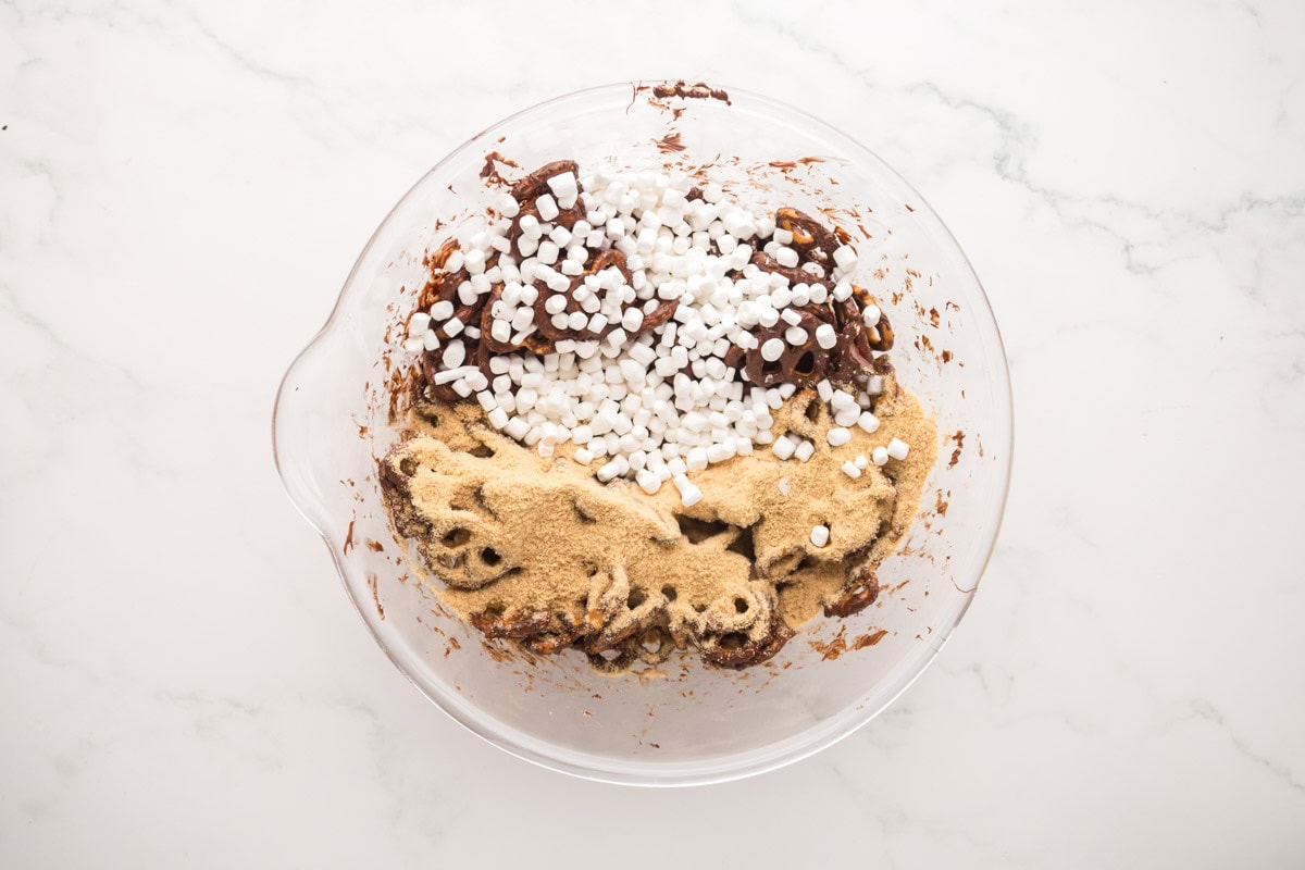 Crushed graham crackers and mini marshmallows added to the bowl of pretzels.