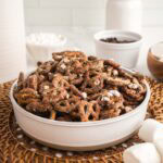 Heaping bowl of s'mores pretzels next to marshmallows.