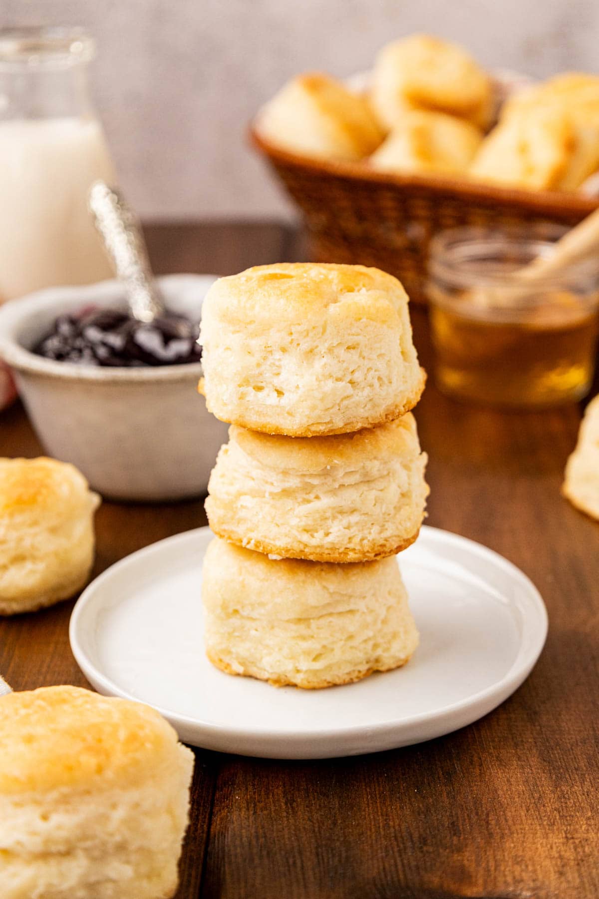 Three southern buttermilk biscuits stacked on top of each other on a white plate.