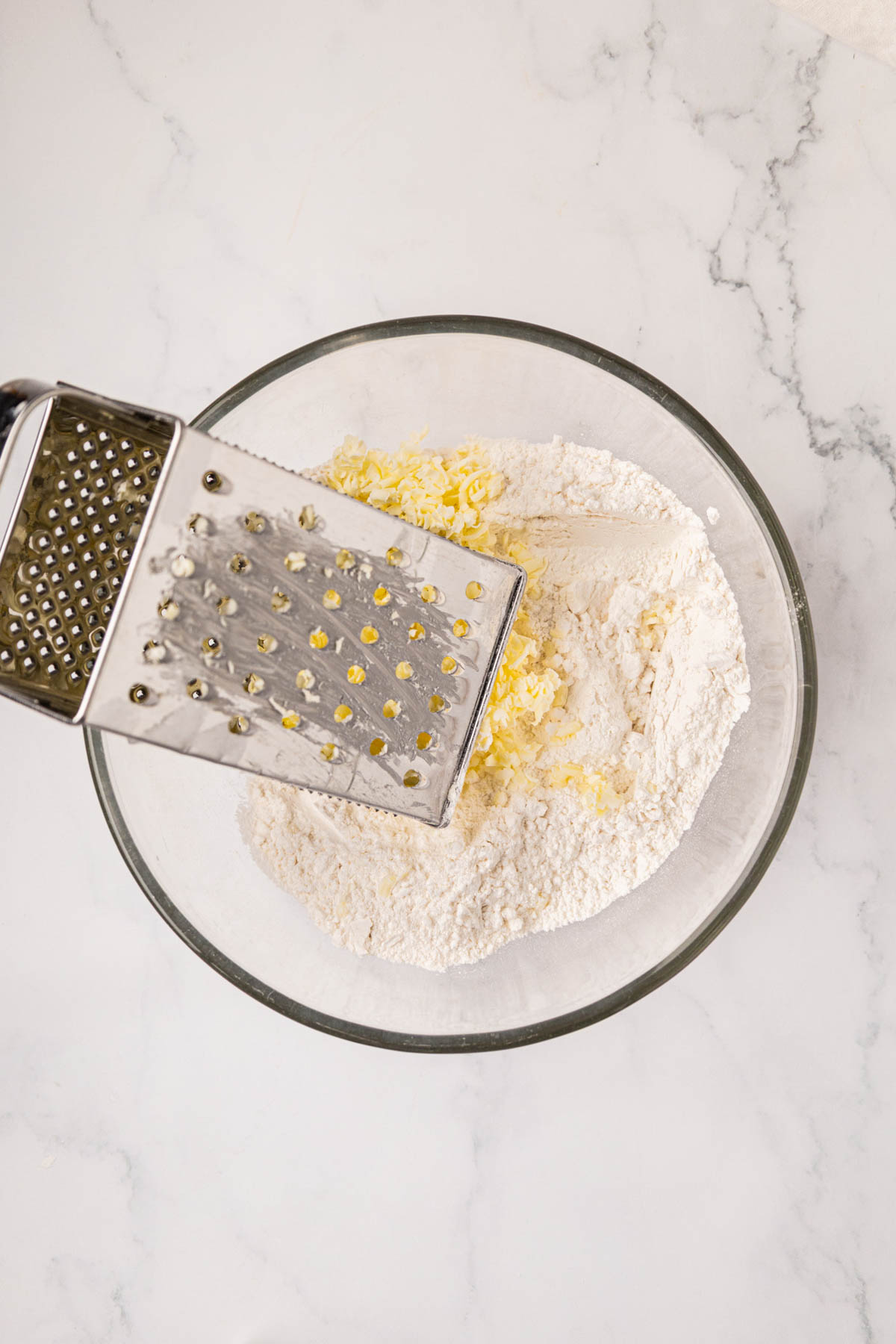 Use a block grater to grate cold butter into flour.