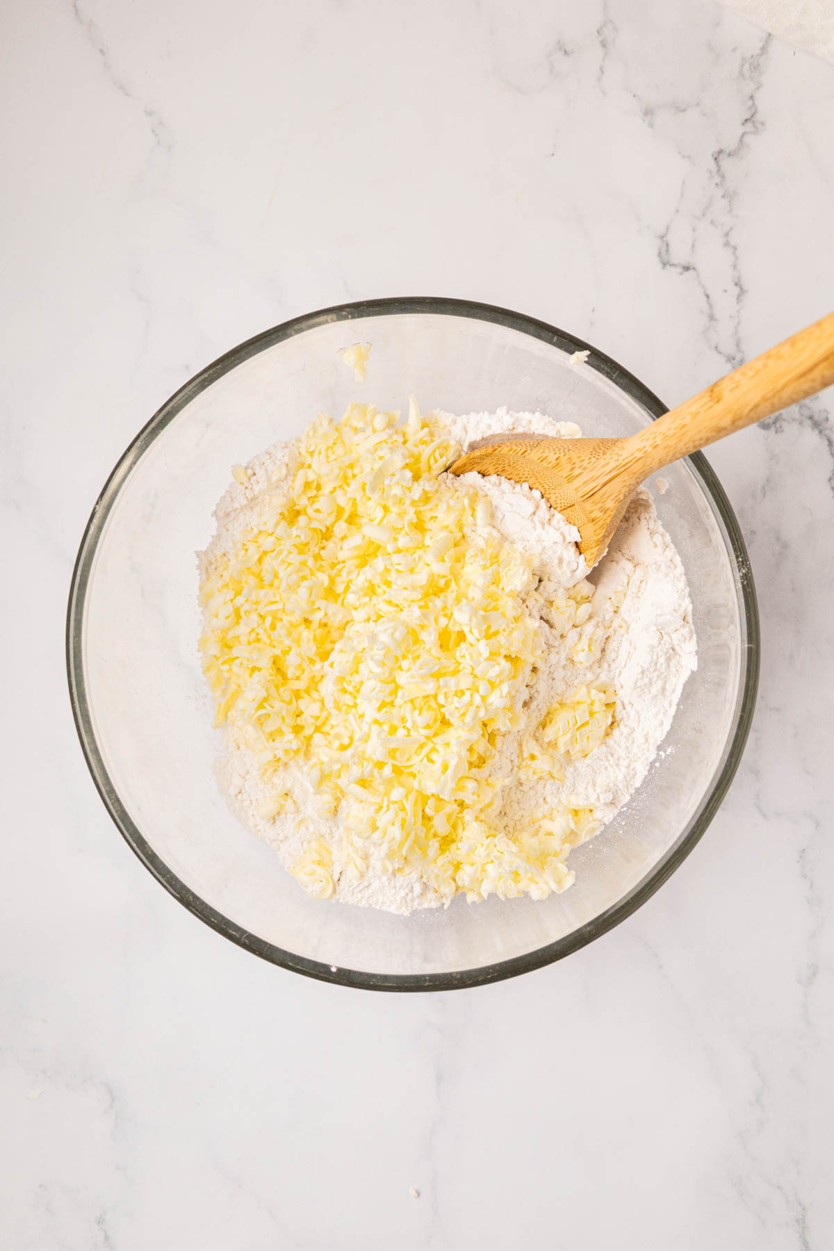 A wooden spoon stirring butter into flour.