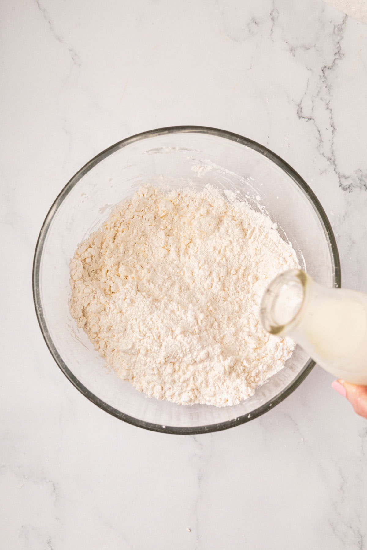 Pouring buttermilk into flour in a bowl.