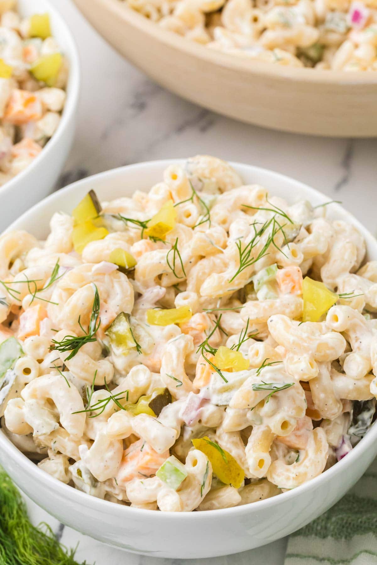 Bowl of dill pickle pasta salad garnished with fresh dill.