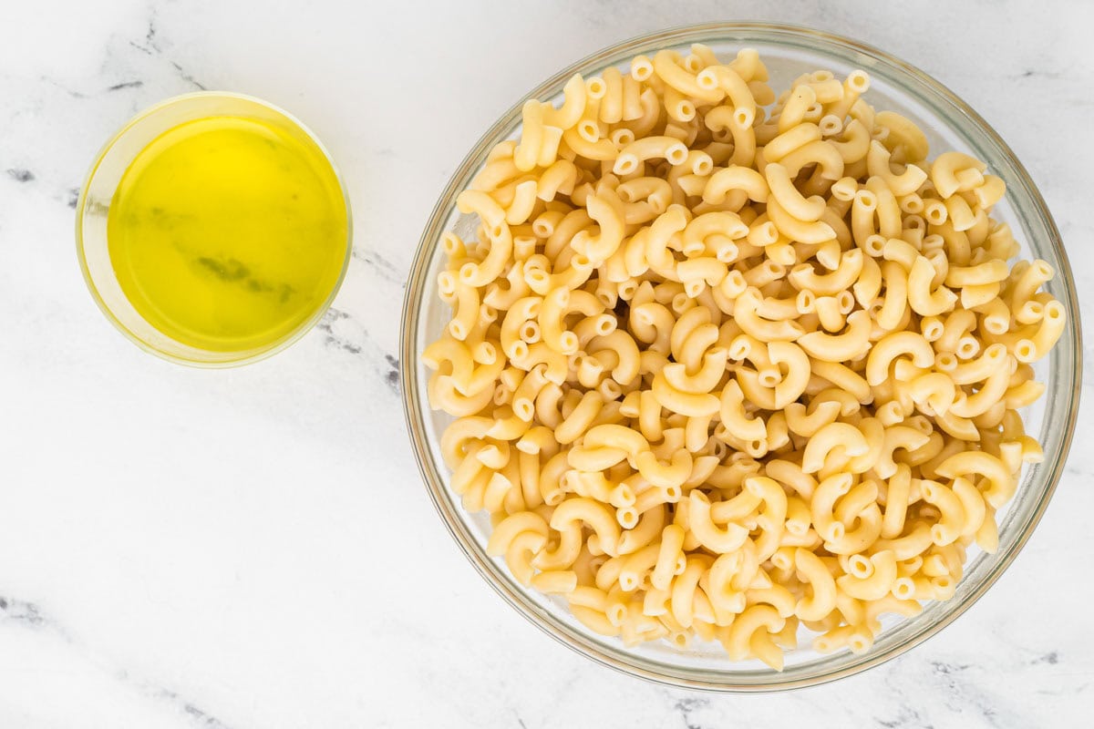 Cooked pasta in a bowl with pickle juice in a bowl next to it.