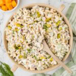 Overhead shot of dill pickle pasta salad in a large bowl with a wooden spoon.