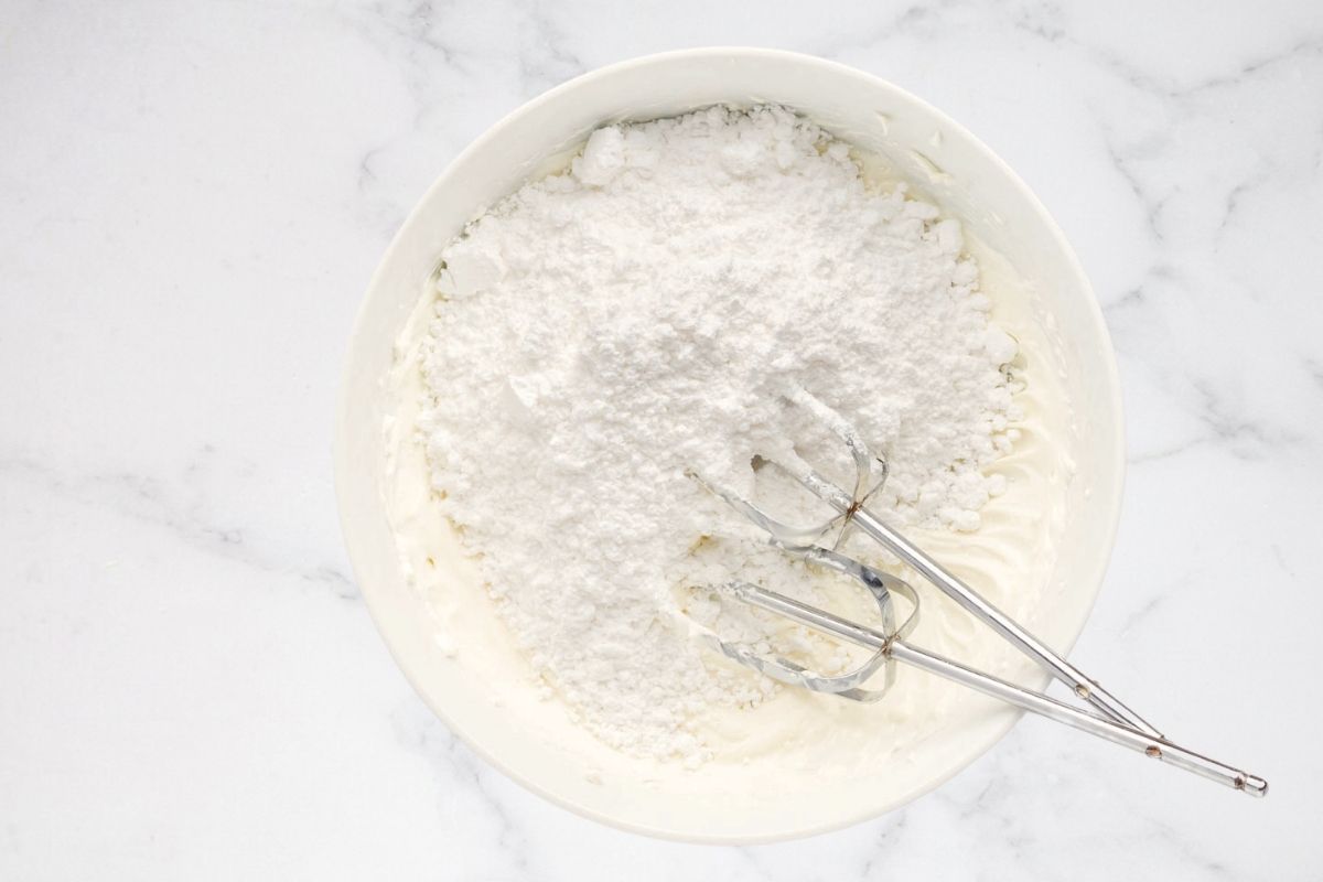 Creamed butter and powdered sugar in a bowl with beaters.