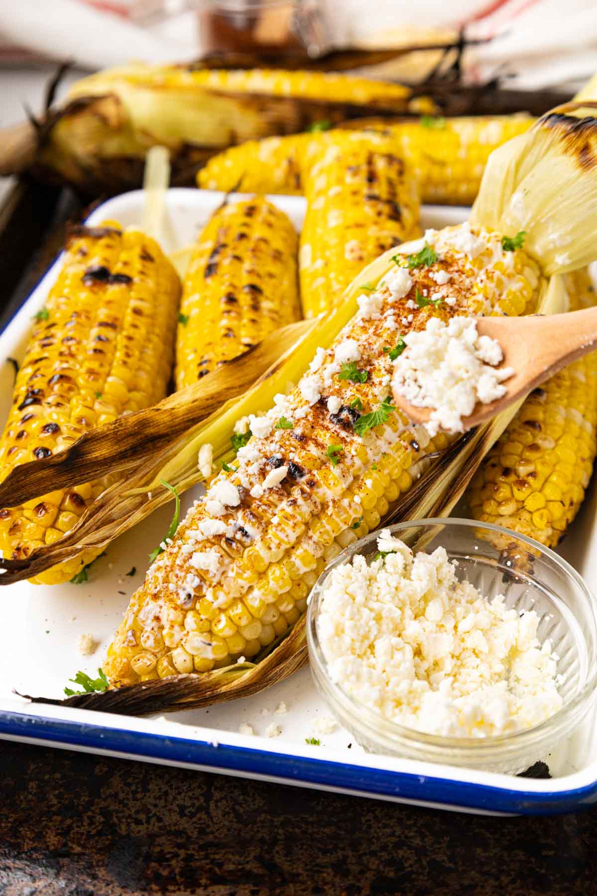 Sprinkling Cotija cheese over the mayo mixture on elote.