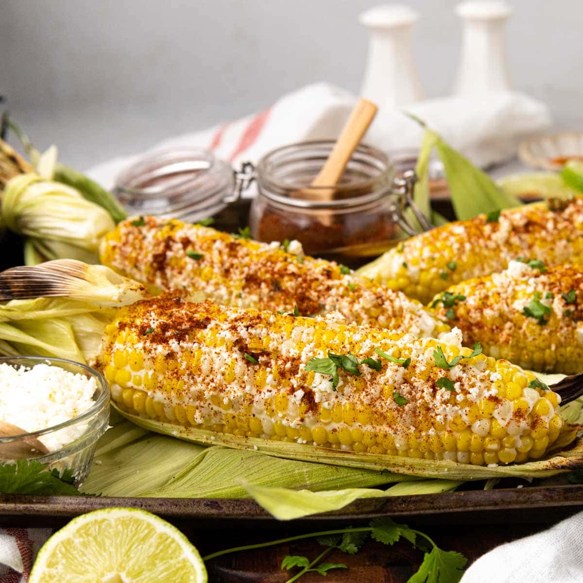 Grilled elote on a tray with all the toppings.