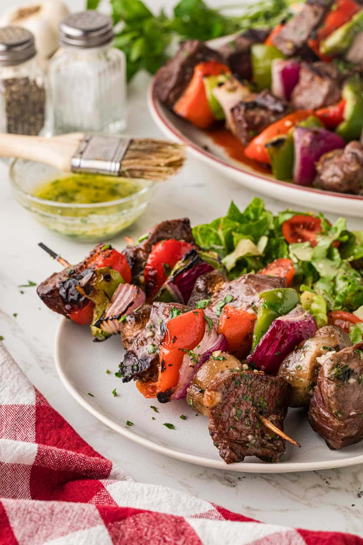 Garlic Butter steak shish kabobs on a plate with salad.