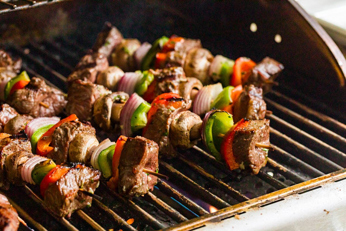 Steak Shish Kabobs cooking on a grill.