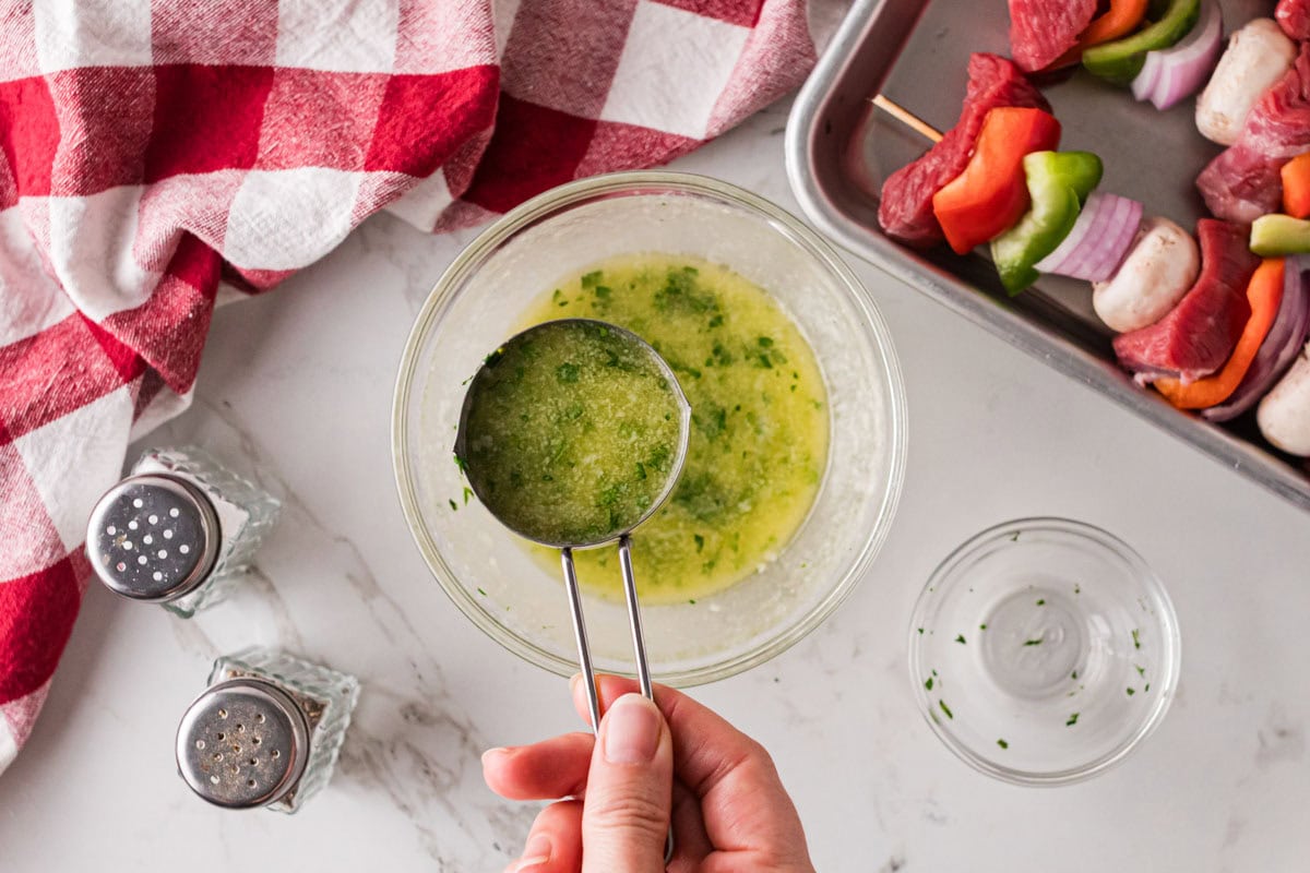 A measuring cup removing part of the marinade to use later.