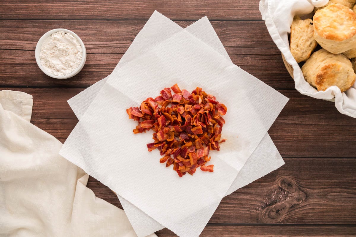 Cooked bacon pieces on a paper towel lined plate.