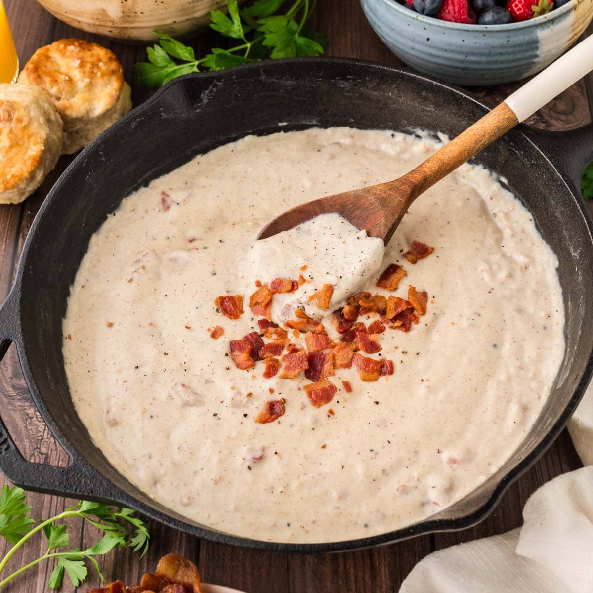 Bacon gravy in a cast iron skillet topped with crumbled bacon and cracked black pepper.