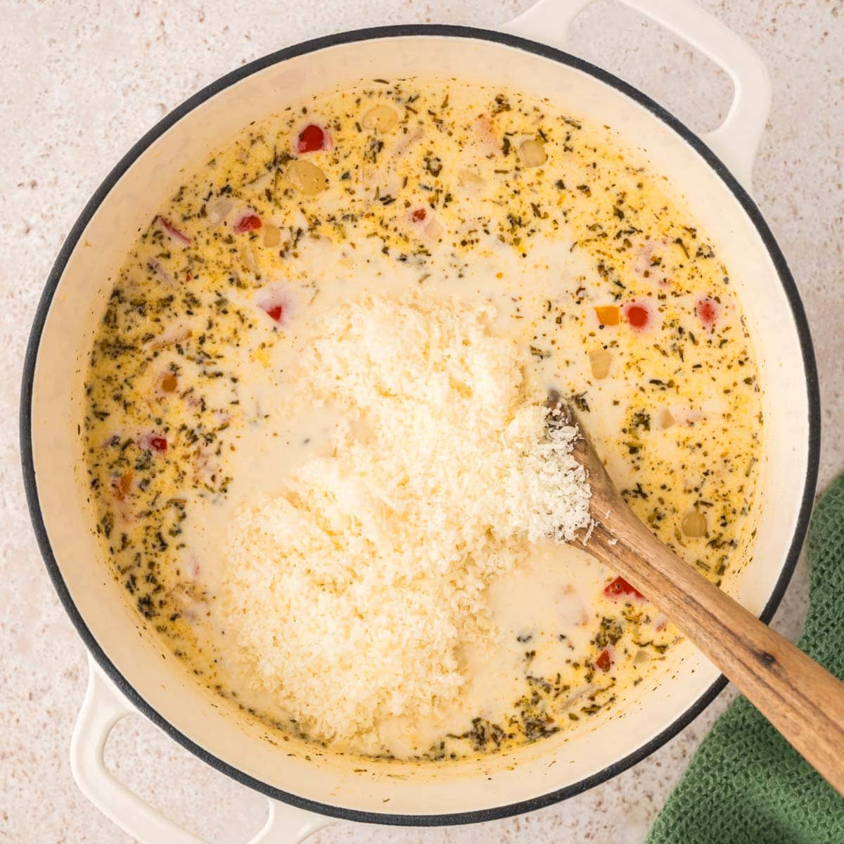 Adding parmesan cheese to the Italian sausage soup.