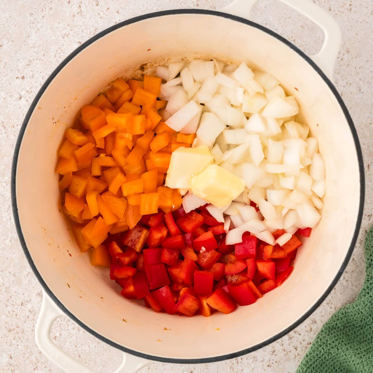 Butter, onions, and peppers added to the Dutch oven to cook.