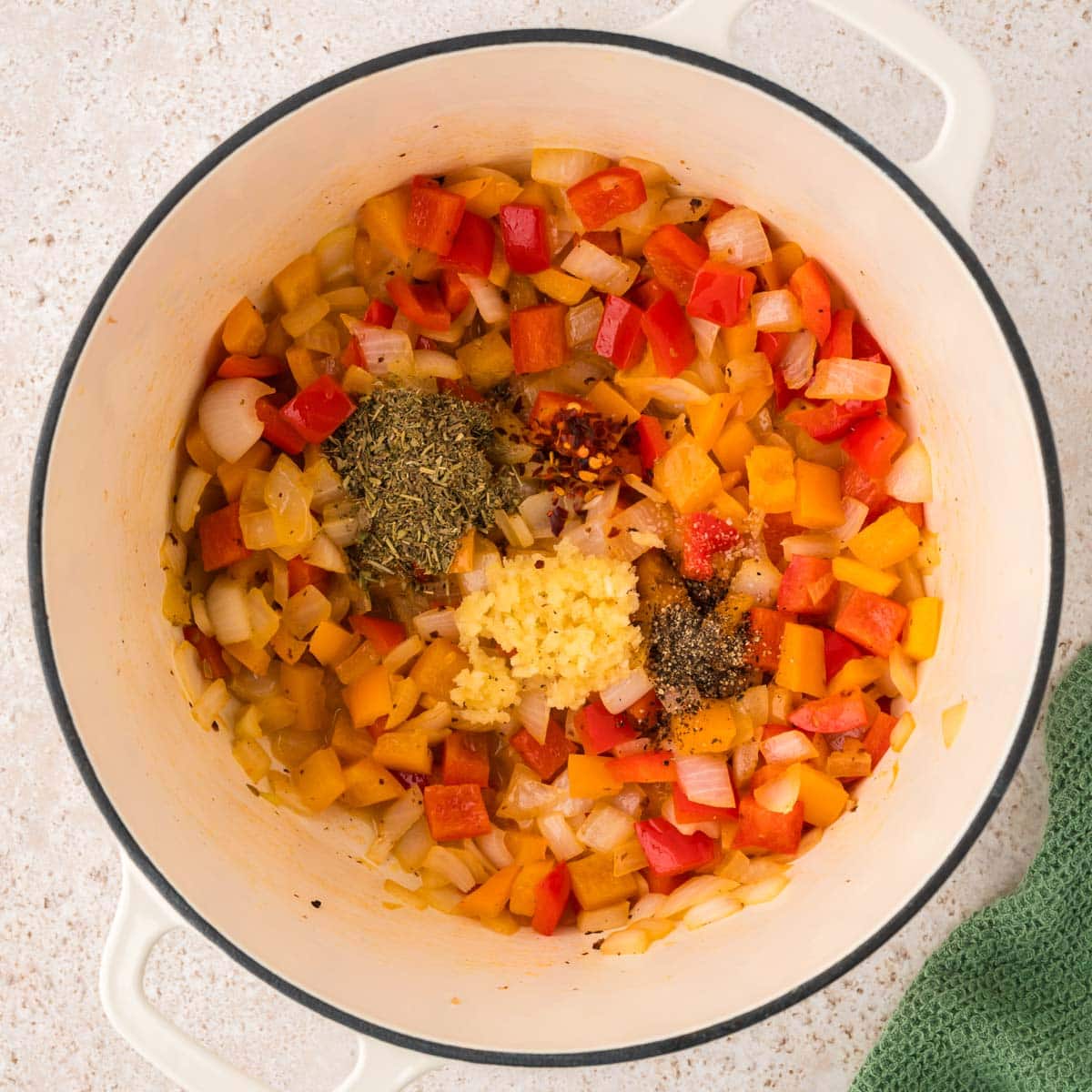 Garlic and spices added to the onions and peppers in a Dutch oven pot.
