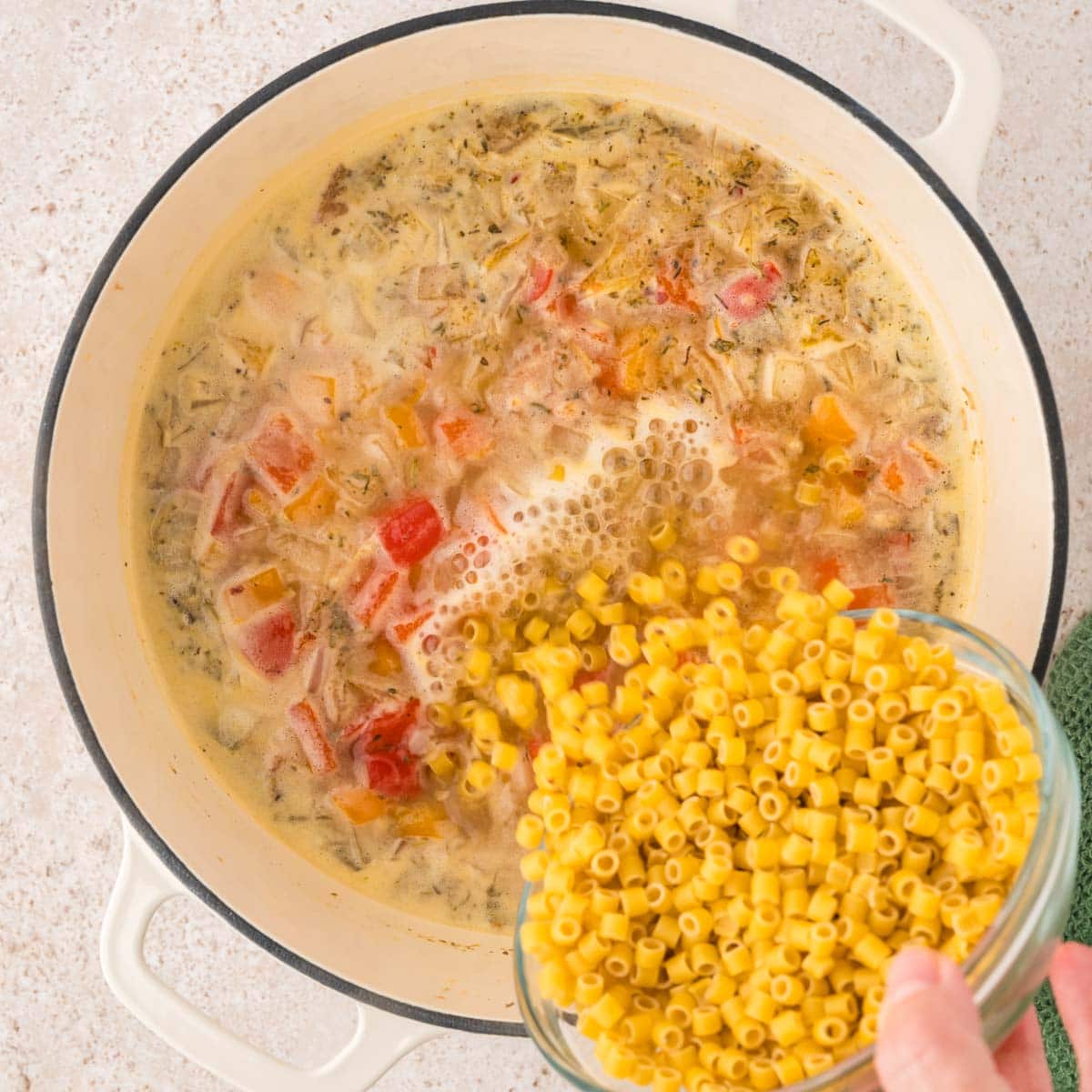 Ditalini pasta added to the soup in a Dutch oven pot.