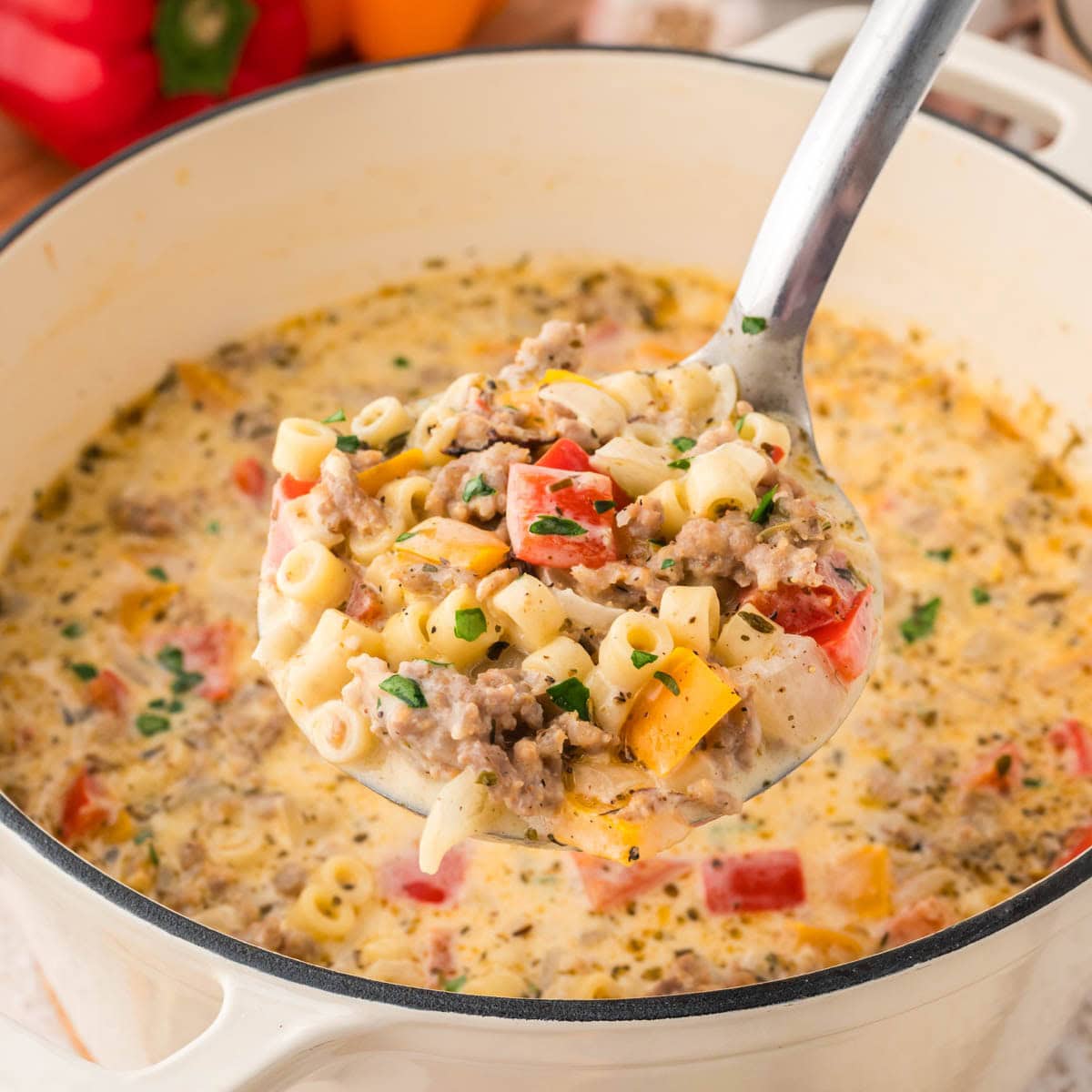 Large ladle of Italian sausage soup scooped from a soup pot.