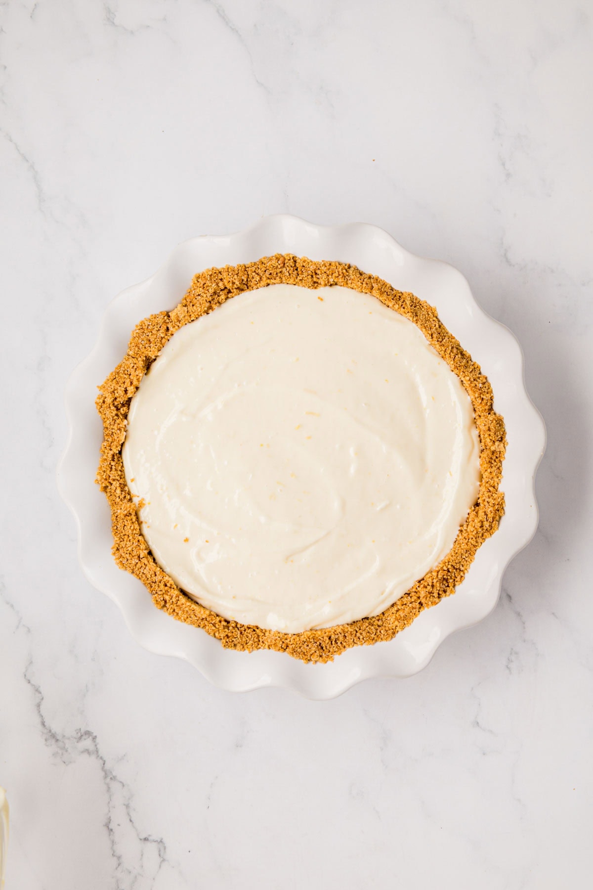 Pie crust filled and smoothed with lemon cheesecake filling.
