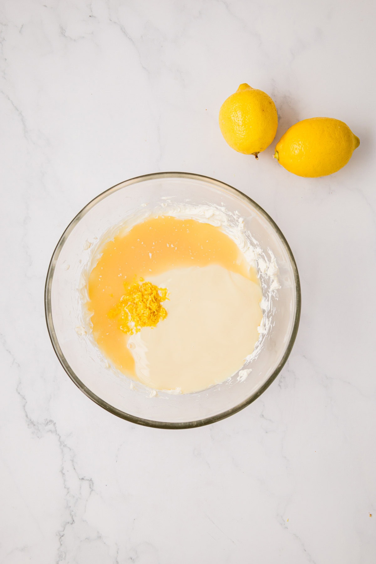Sweetened condensed milk, lemon juice and zest added to the bowl of beaten cream cheese.