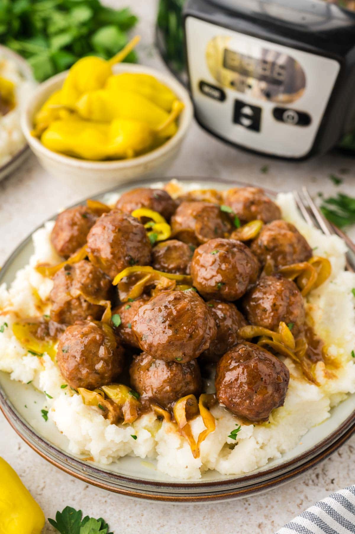 Mississippi meatballs served on a bed of mashed potatoes on a plate.